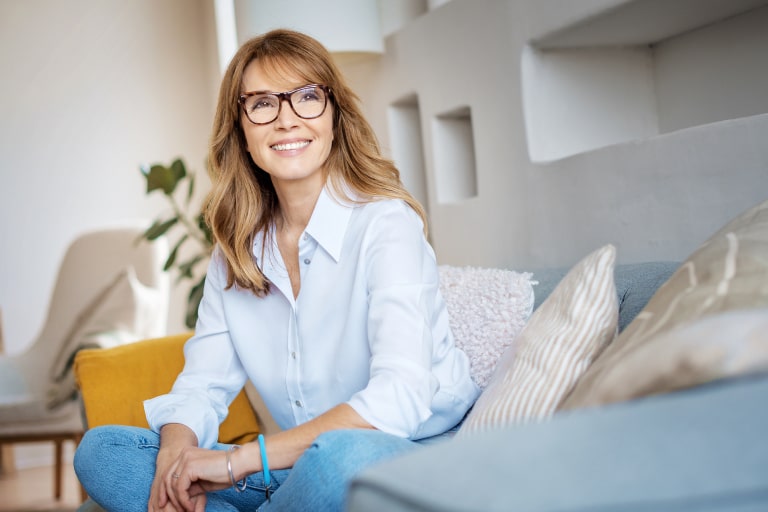 Portrait shot happy mature woman relaxing on couch at home.