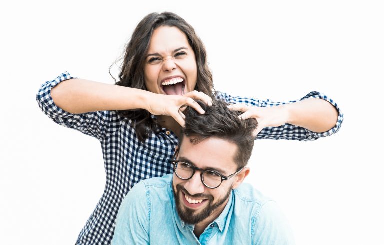 Excited joyful woman setting funny hair of her happy boyfriend