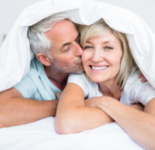 Closeup of mature man kissing womans cheek in bed