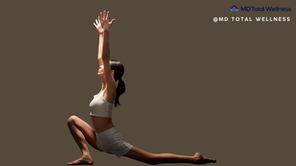 The Difference Between a Wellness Center and a MedSpa: What OC Patients Should Know 1 Woman in gray athletic wear performs a yoga lunge pose with arms raised against neutral background in integrative medicine clinic OC