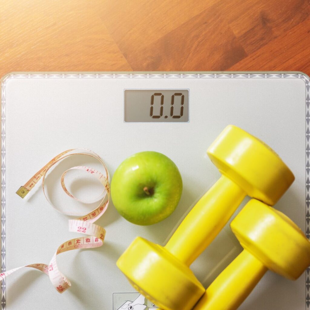 weight loss scale and food and dumbells and apple